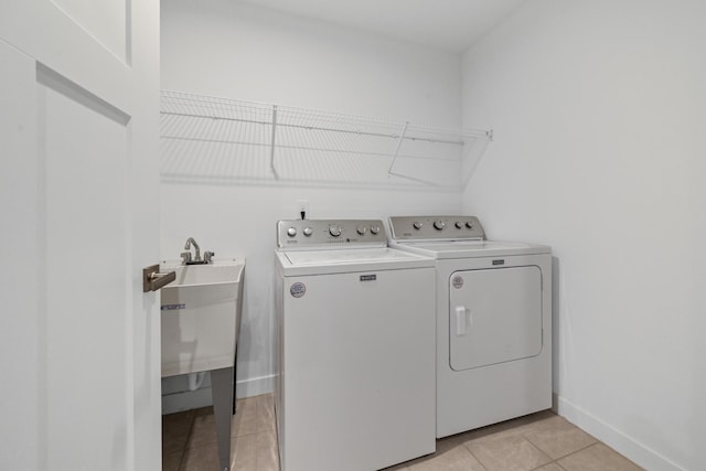 washroom featuring light tile patterned floors, a sink, washer and dryer, laundry area, and baseboards