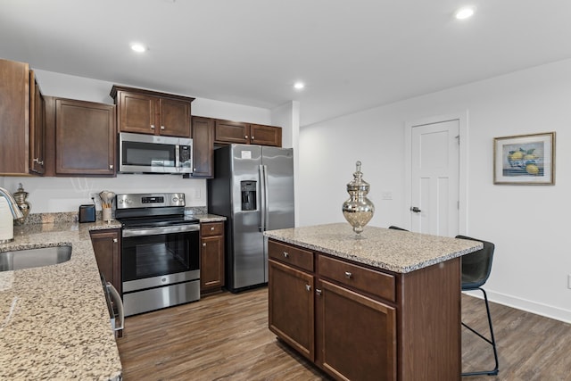 kitchen featuring recessed lighting, a breakfast bar, dark wood-style flooring, a sink, and appliances with stainless steel finishes