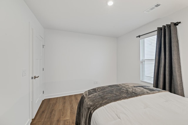 bedroom featuring baseboards, visible vents, and wood finished floors