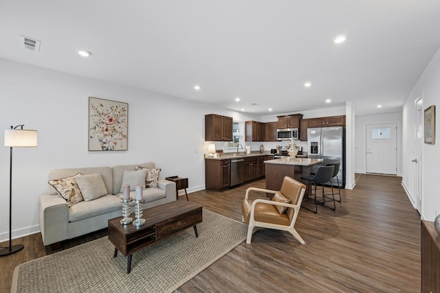 living room with dark wood-type flooring, visible vents, and recessed lighting