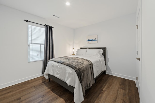 bedroom with visible vents, baseboards, and wood finished floors