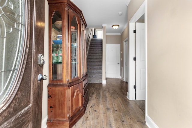 hall with ornamental molding, stairway, baseboards, and wood finished floors