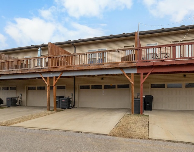 back of property with a garage, central AC, and concrete driveway