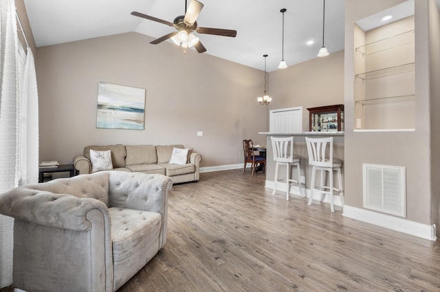 living room with baseboards, visible vents, wood finished floors, vaulted ceiling, and ceiling fan with notable chandelier