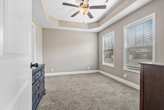 interior space featuring baseboards, visible vents, a tray ceiling, and ceiling fan