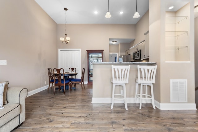 kitchen featuring stainless steel appliances, a breakfast bar, visible vents, and wood finished floors