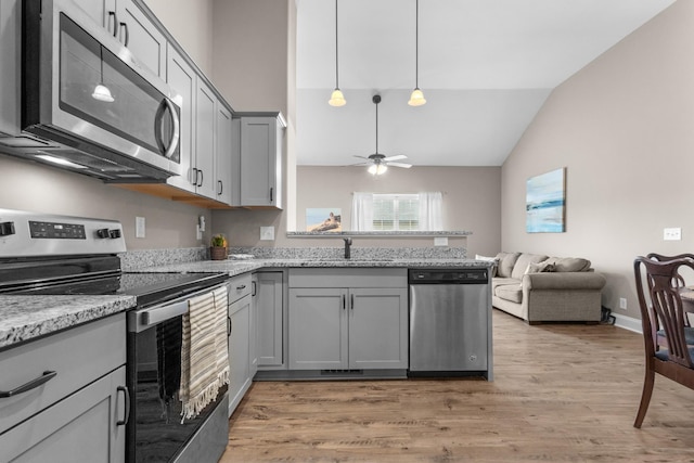 kitchen featuring gray cabinets, appliances with stainless steel finishes, light wood-style floors, a sink, and a peninsula