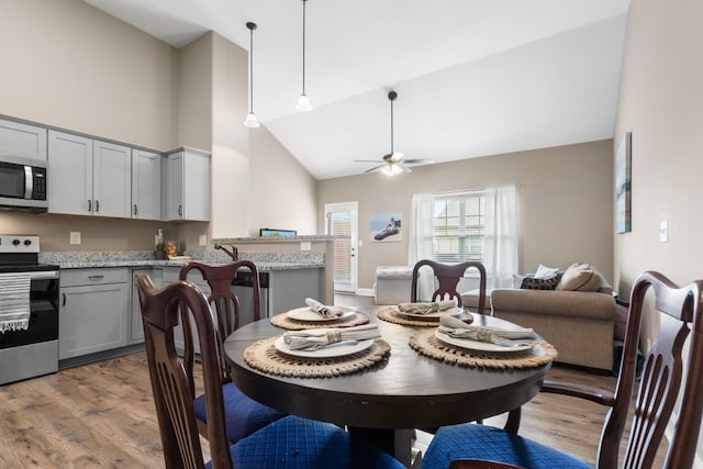 dining room with high vaulted ceiling, ceiling fan, and wood finished floors