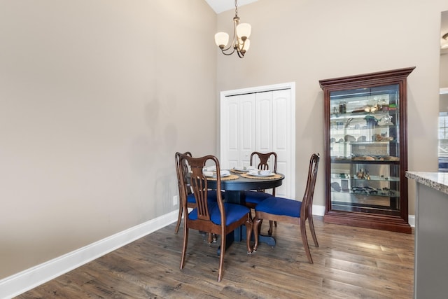 dining area with baseboards, wood finished floors, and an inviting chandelier