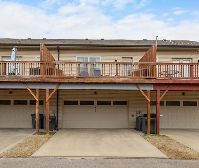 back of property with a garage, driveway, and central air condition unit