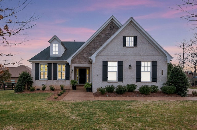 traditional home featuring brick siding, a front yard, and fence