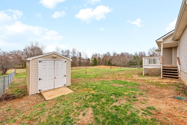 view of yard with a wooden deck, fence, a storage unit, and an outdoor structure