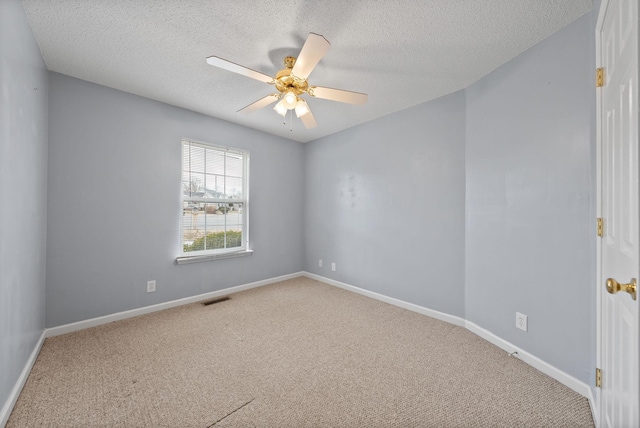 spare room with baseboards, carpet floors, visible vents, and a ceiling fan