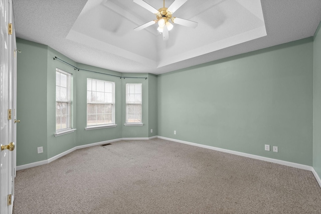 carpeted spare room with a raised ceiling, visible vents, and baseboards