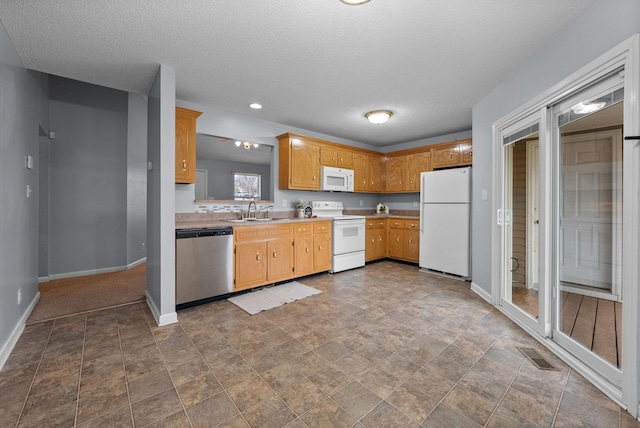 kitchen with white appliances, baseboards, visible vents, light countertops, and a sink