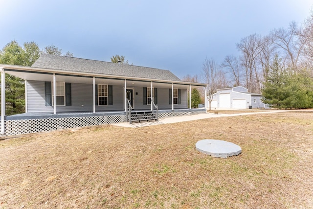 view of front of home with an outbuilding, roof with shingles, a detached garage, a porch, and a front yard