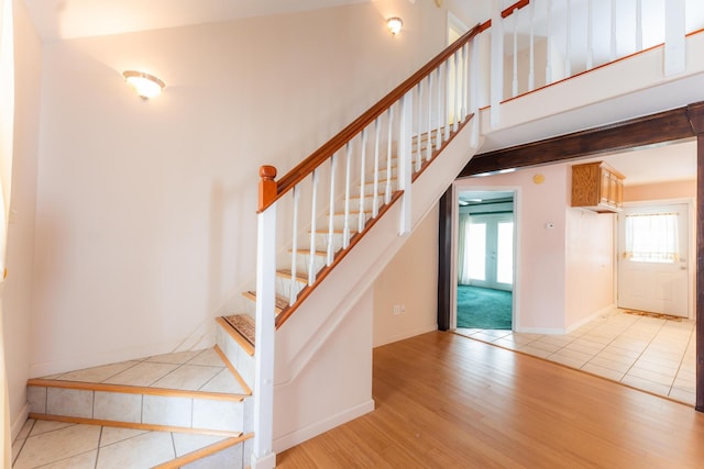 stairway featuring a high ceiling, wood finished floors, and baseboards