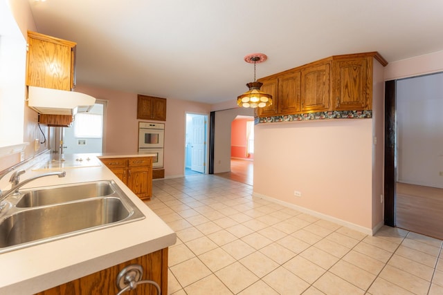 kitchen featuring brown cabinetry, light tile patterned flooring, and a sink