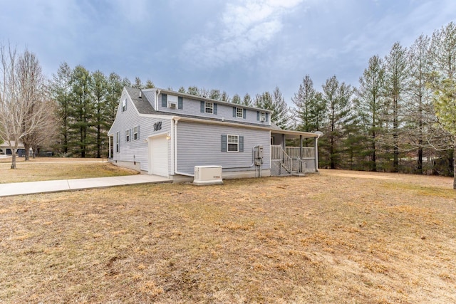 back of house with covered porch, a yard, and concrete driveway