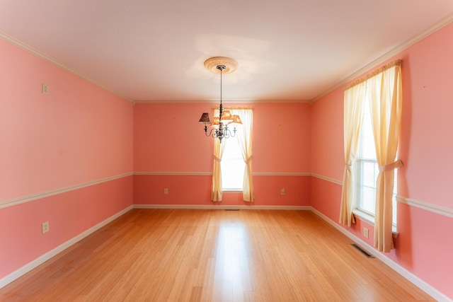 empty room with a notable chandelier, visible vents, baseboards, light wood-style floors, and ornamental molding