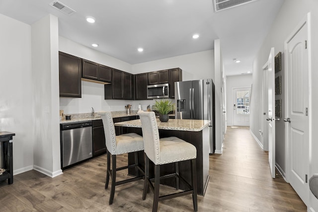 kitchen featuring visible vents, stainless steel appliances, dark brown cabinets, and wood finished floors