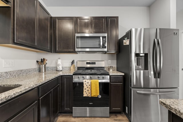 kitchen featuring stainless steel appliances, light wood-style flooring, and dark brown cabinets