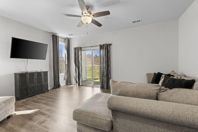 living room featuring light wood-style flooring, visible vents, and ceiling fan