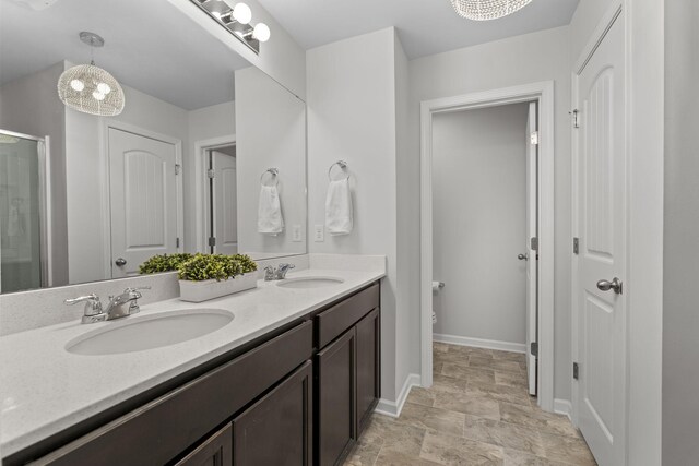 bathroom featuring baseboards, double vanity, a sink, and a shower stall