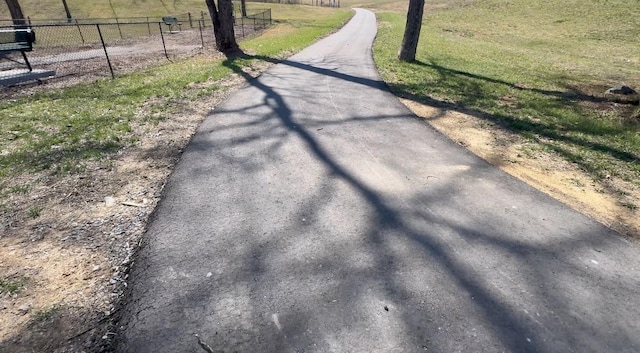 surrounding community featuring aphalt driveway, a lawn, and fence