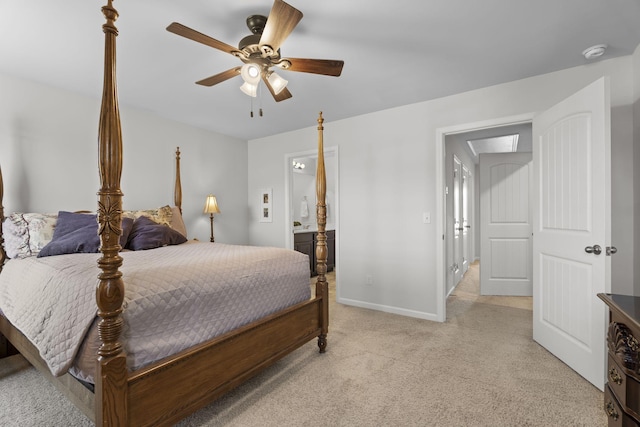 bedroom featuring baseboards, ceiling fan, ensuite bath, and light colored carpet