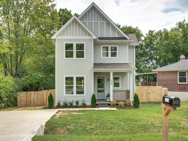 view of front facade featuring covered porch, board and batten siding, a front yard, and fence