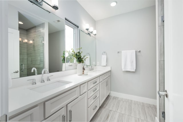 bathroom featuring double vanity, baseboards, a stall shower, and a sink