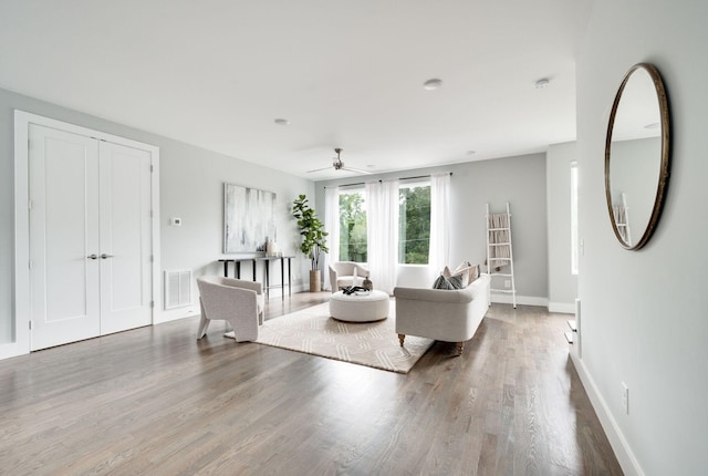 living area featuring ceiling fan, visible vents, baseboards, and wood finished floors