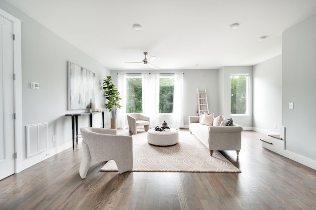 living area featuring visible vents, ceiling fan, baseboards, and wood finished floors