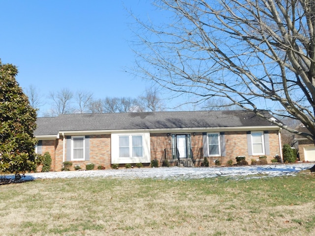 ranch-style home with brick siding, a front lawn, and roof with shingles