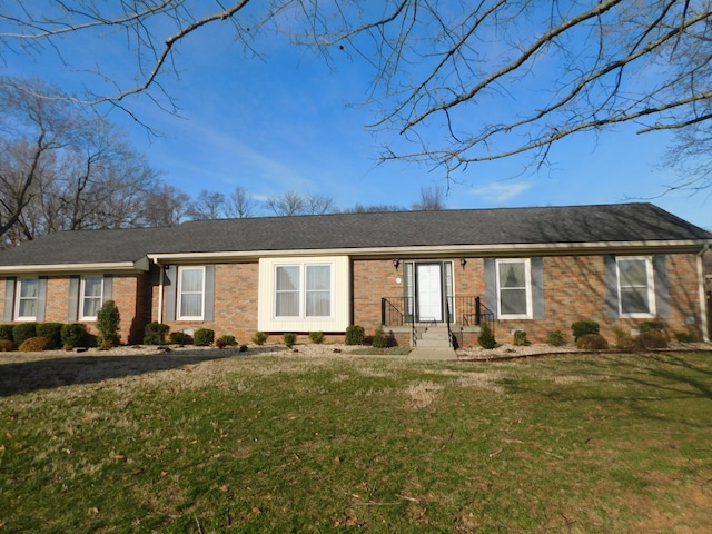 ranch-style house with brick siding, a front lawn, and roof with shingles