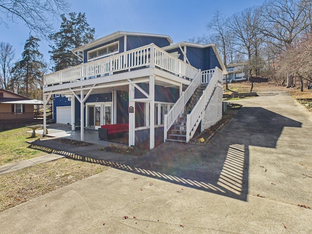 view of front of house featuring a garage, driveway, a deck, and stairway