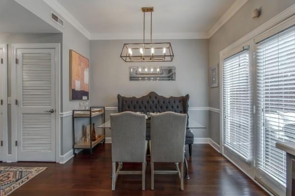 dining area featuring dark wood-style floors, visible vents, and crown molding