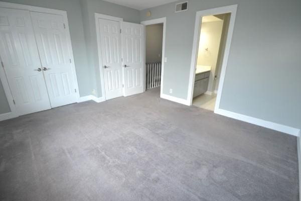 unfurnished bedroom featuring carpet floors, visible vents, connected bathroom, and baseboards