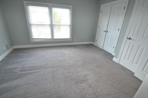 unfurnished bedroom featuring carpet floors, a closet, and baseboards