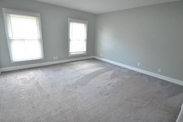 unfurnished room with carpet and baseboards