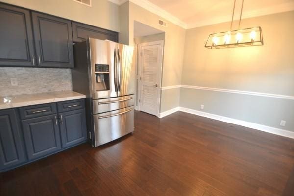 kitchen featuring dark wood-style floors, light countertops, stainless steel fridge, and decorative backsplash