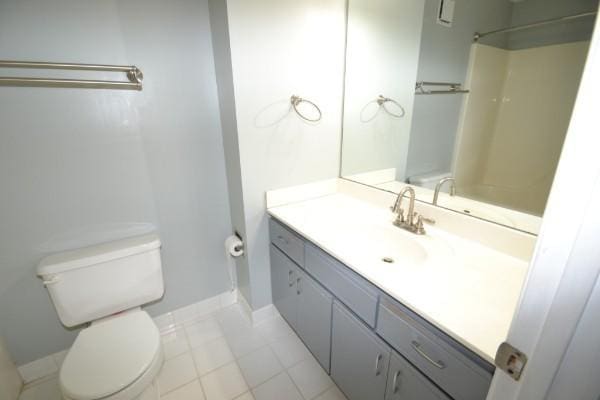 full bathroom featuring toilet, tile patterned floors, baseboards, and vanity