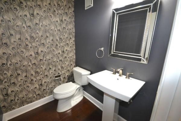 bathroom featuring toilet, baseboards, a shower, and wood finished floors