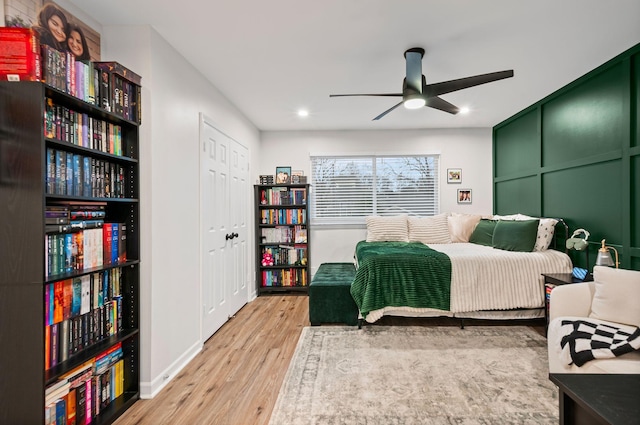 bedroom featuring ceiling fan, a decorative wall, and wood finished floors