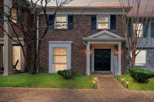 view of front facade featuring a front yard, french doors, and brick siding