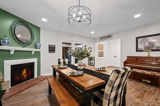 dining space featuring a chandelier, recessed lighting, a fireplace, and wood finished floors