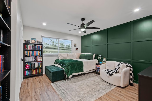 bedroom featuring light wood-style floors, ceiling fan, a decorative wall, and recessed lighting