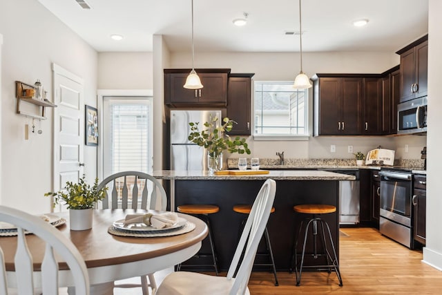 kitchen featuring visible vents, stainless steel appliances, light wood-type flooring, and dark brown cabinetry