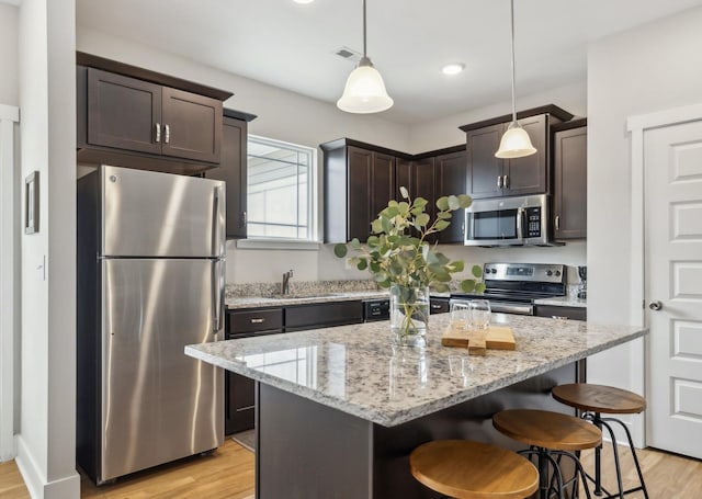 kitchen featuring dark brown cabinets, appliances with stainless steel finishes, a sink, and a kitchen breakfast bar